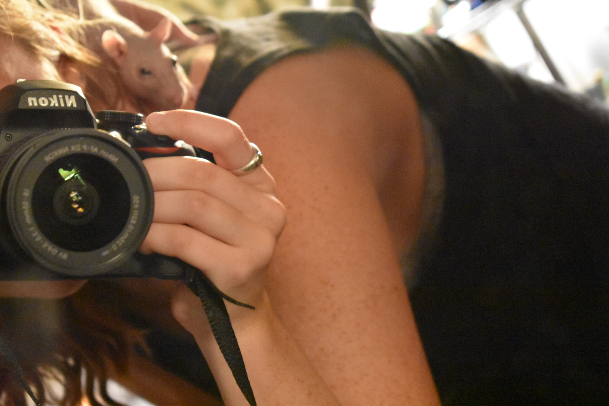 close up of a camera, no face shown, with a naked rat sitting on brianna's shoulder